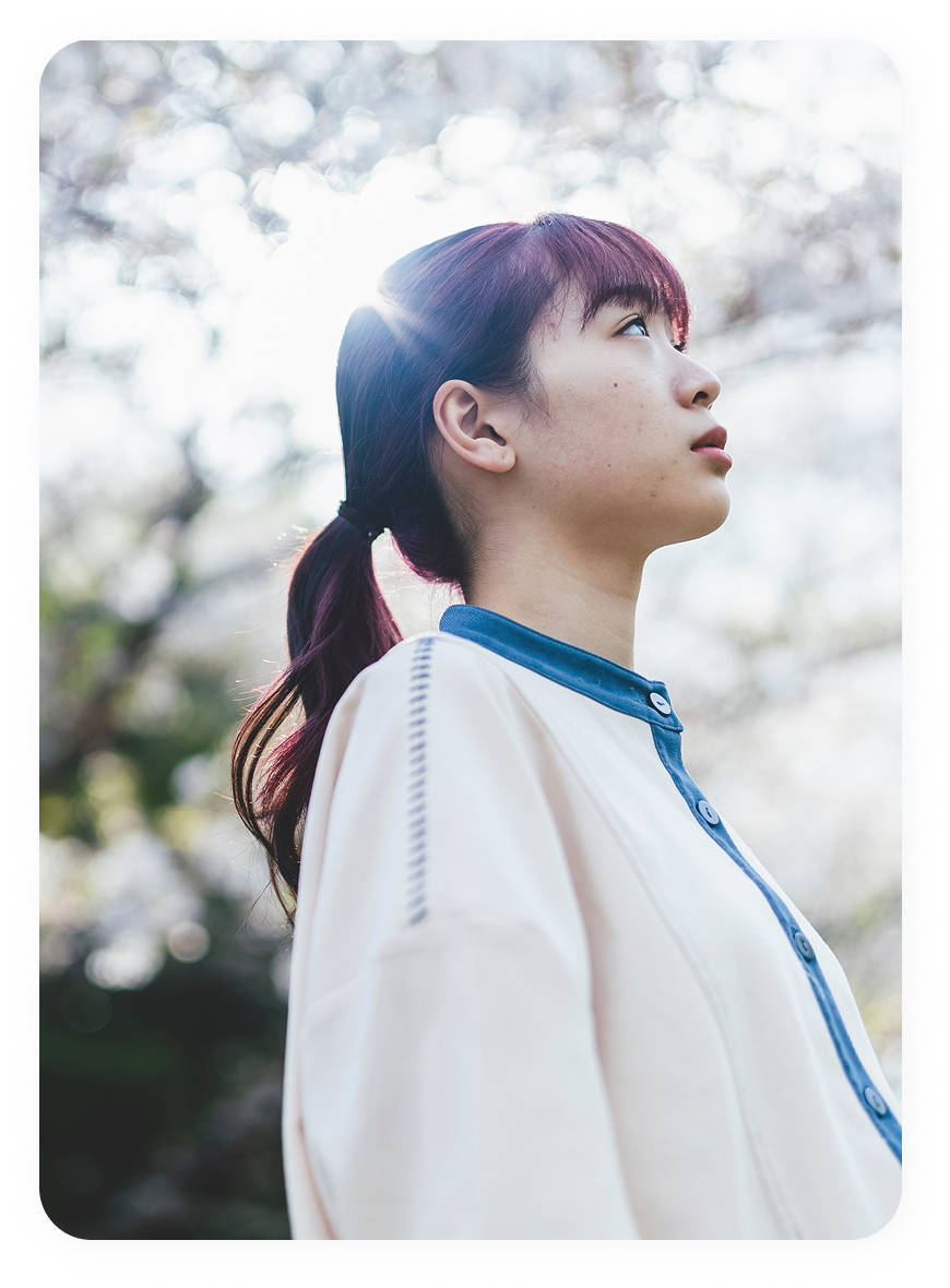 屋外で空を見上げる若い女性