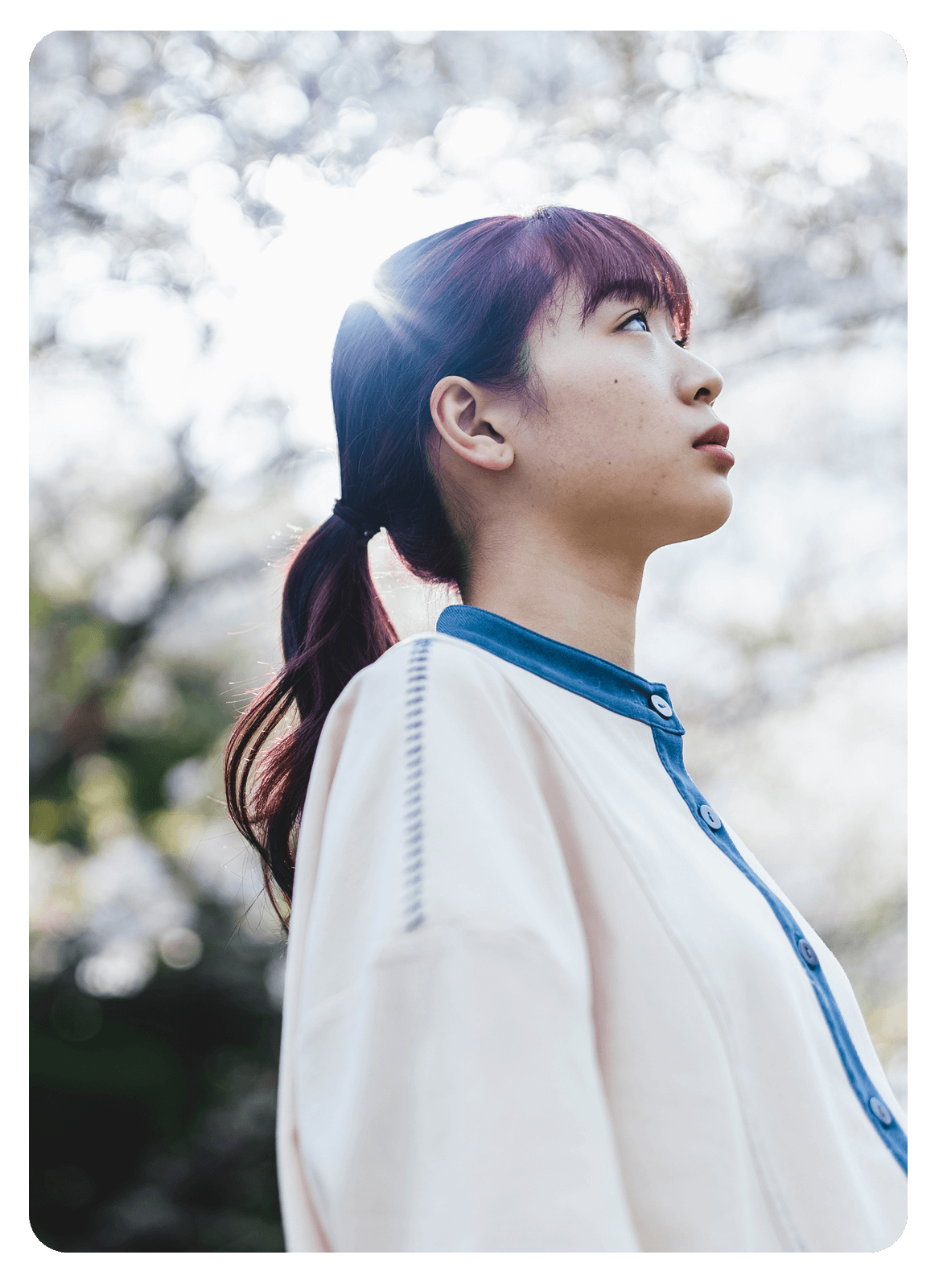 屋外で空を見上げる若い女性