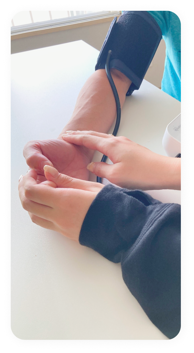 スタッフが手を添えて血圧測定をする様子