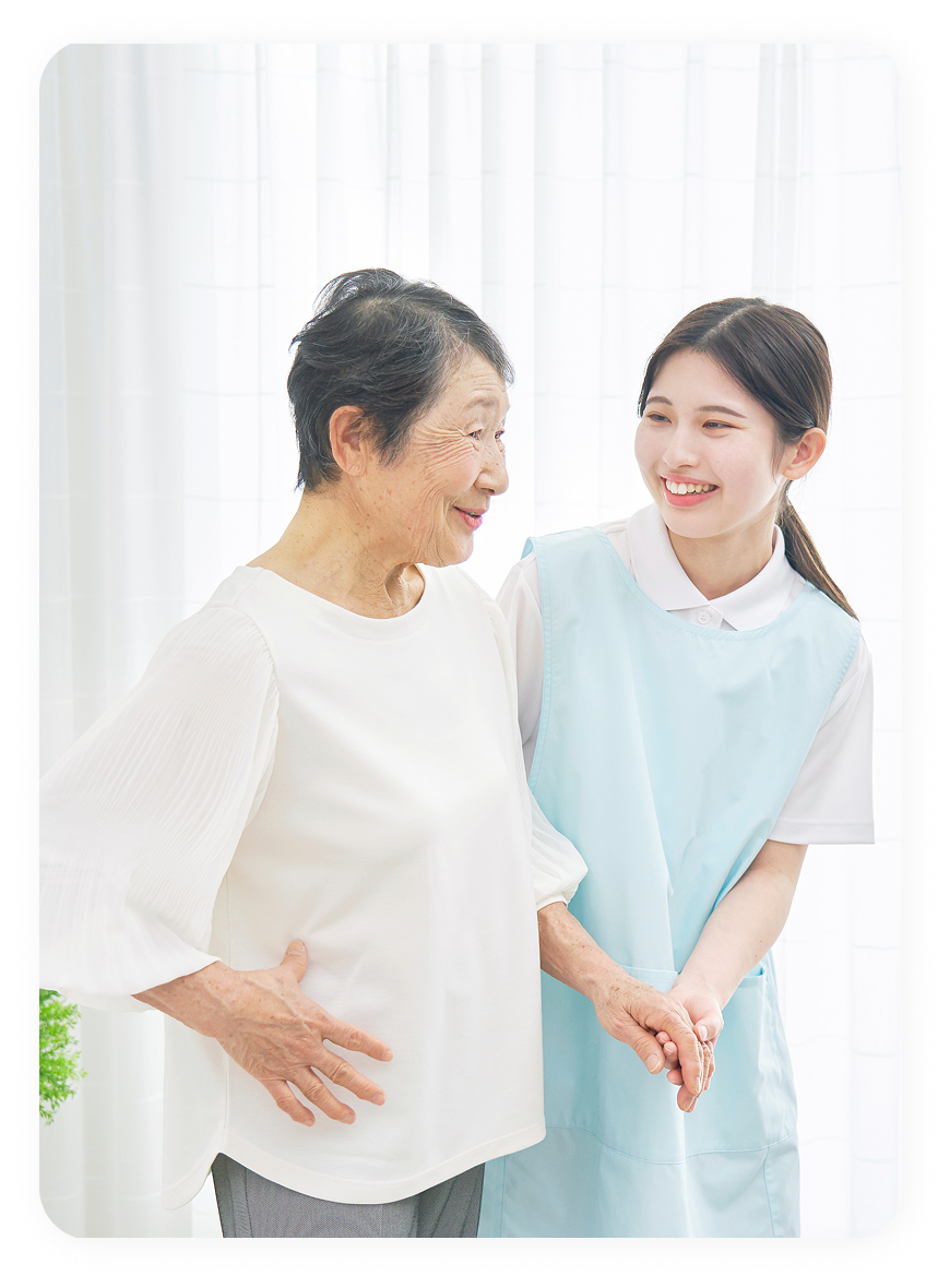 介護士に支えられ笑顔で会話する高齢女性